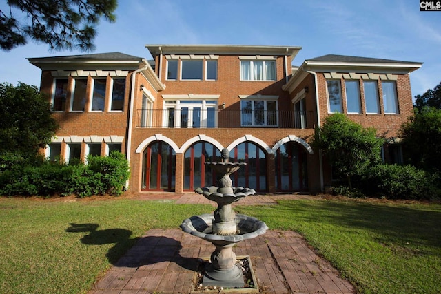 rear view of house with a balcony and a yard