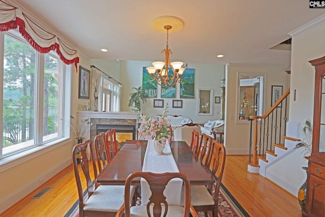 dining room featuring light hardwood / wood-style flooring, a notable chandelier, and a premium fireplace