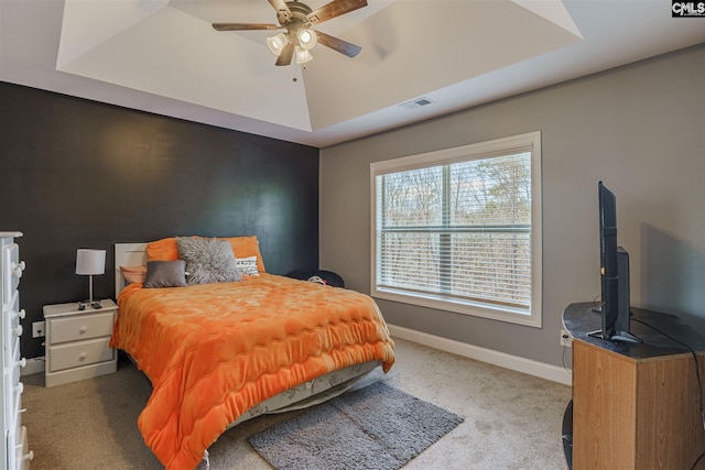 carpeted bedroom featuring a raised ceiling and ceiling fan