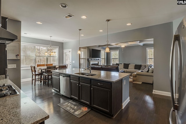 kitchen featuring dark hardwood / wood-style flooring, a notable chandelier, appliances with stainless steel finishes, and light stone counters