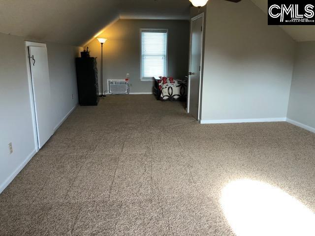 bonus room with dark carpet, vaulted ceiling, and ceiling fan