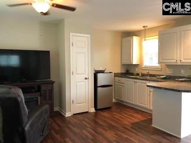 kitchen featuring pendant lighting, ceiling fan, dark hardwood / wood-style flooring, white cabinets, and stainless steel refrigerator