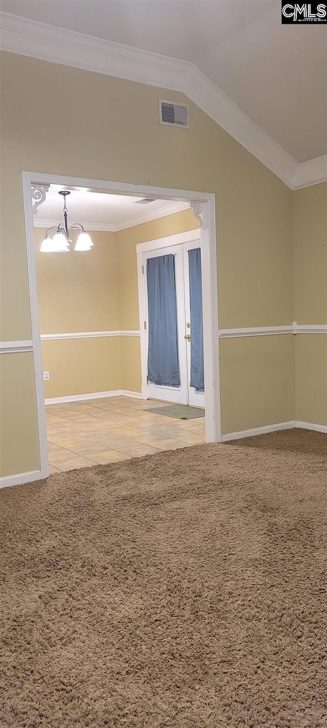 carpeted spare room featuring french doors, an inviting chandelier, and ornamental molding