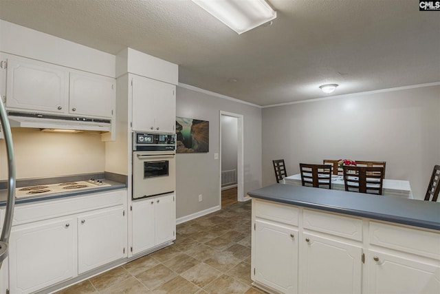 kitchen featuring white appliances, light tile floors, ornamental molding, white cabinets, and a textured ceiling