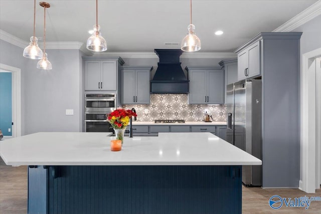 kitchen with hanging light fixtures, stainless steel appliances, custom range hood, and light wood-type flooring