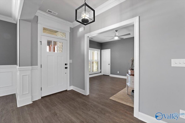 entrance foyer with ceiling fan with notable chandelier, dark wood-type flooring, and crown molding