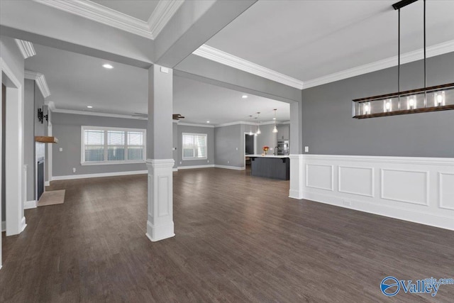 unfurnished living room featuring dark hardwood / wood-style flooring, ornate columns, ceiling fan, and ornamental molding