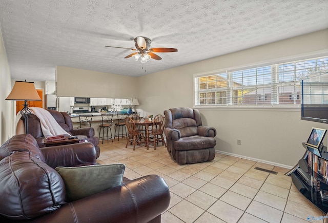 living room featuring ceiling fan, baseboards, light tile patterned flooring, and a textured ceiling