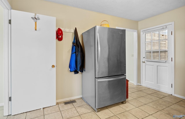 kitchen with freestanding refrigerator, visible vents, baseboards, and light tile patterned floors