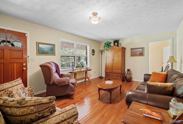 living area featuring a textured ceiling, light wood finished floors, and baseboards
