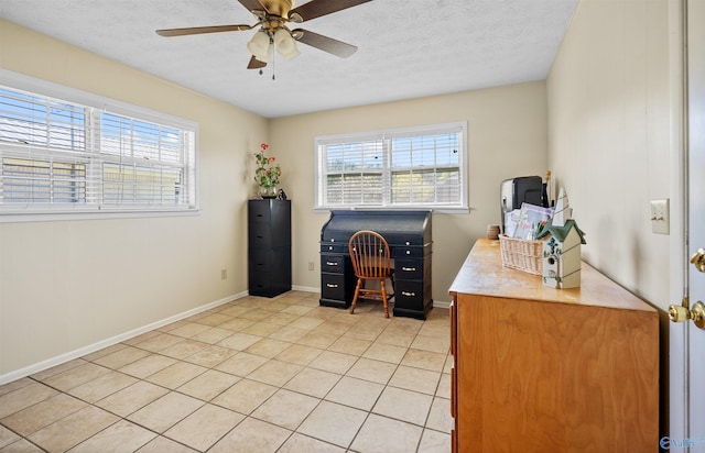 office space featuring a wealth of natural light, a ceiling fan, baseboards, and light tile patterned floors