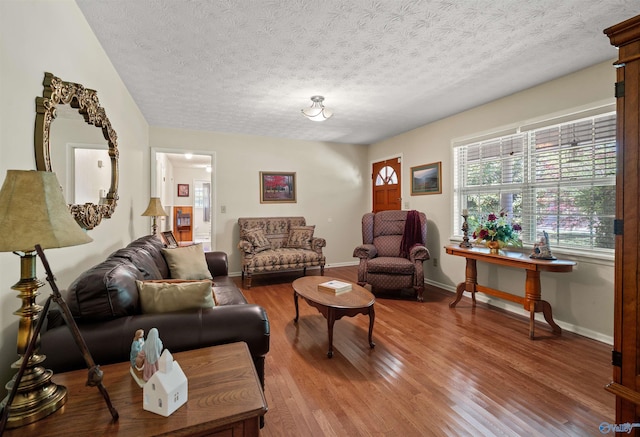 living area with wood finished floors, a textured ceiling, and baseboards
