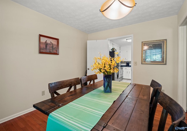 dining area with wood finished floors, a textured ceiling, and baseboards