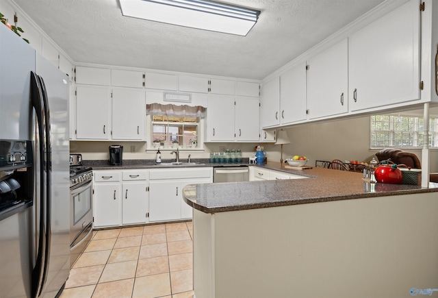 kitchen featuring stainless steel appliances, a sink, a textured ceiling, white cabinetry, and light tile patterned floors