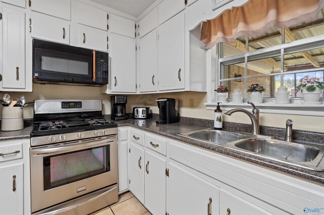 kitchen featuring white cabinets, stainless steel range with gas stovetop, light tile patterned floors, a sink, and black microwave