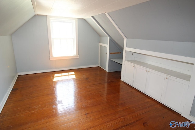 bonus room with dark wood-type flooring and vaulted ceiling