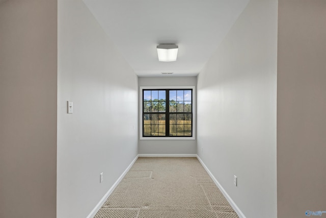 empty room featuring baseboards, visible vents, and light colored carpet