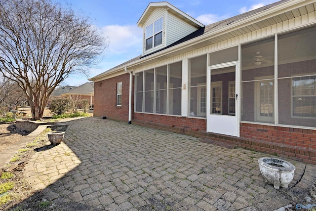 exterior space featuring brick siding, a patio area, and a sunroom