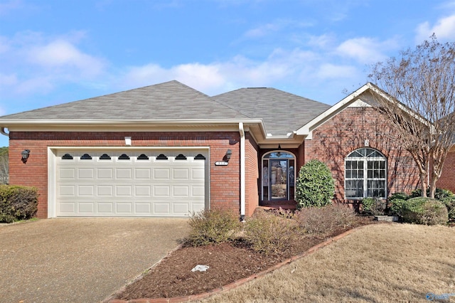 ranch-style house featuring brick siding, driveway, an attached garage, and roof with shingles