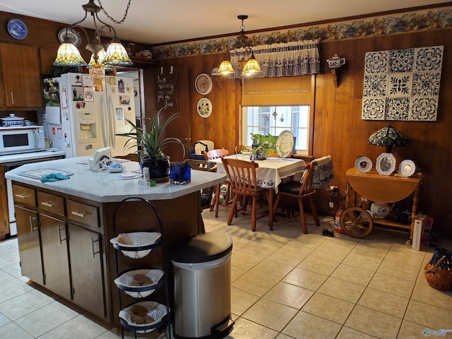 kitchen with light tile patterned flooring, a kitchen island, pendant lighting, dark brown cabinets, and white appliances