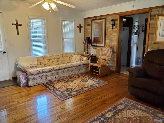 living room with hardwood / wood-style flooring, crown molding, and ceiling fan