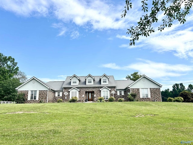 view of front of property featuring a front yard, stone siding, and metal roof