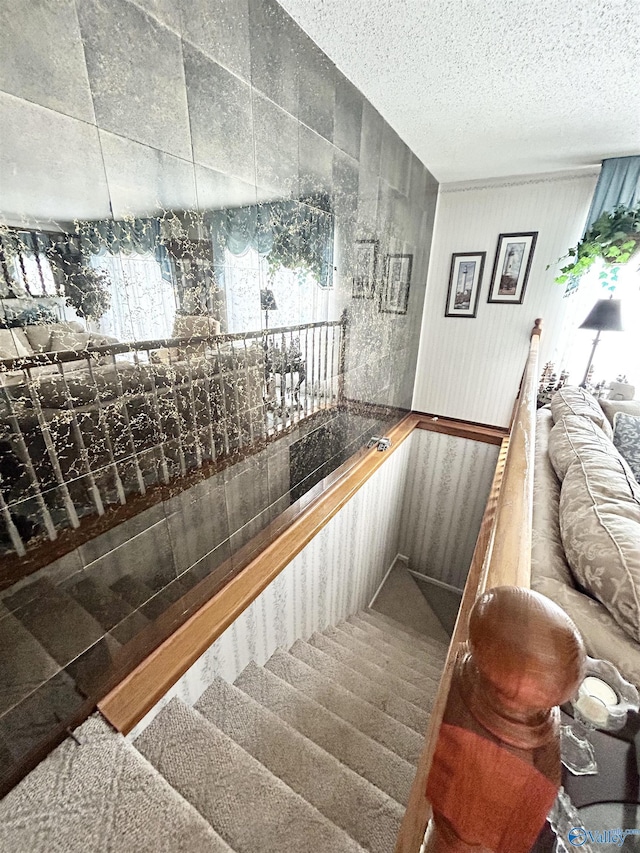 staircase with carpet and a textured ceiling