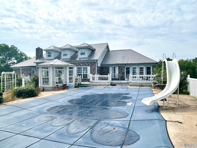 rear view of house featuring a covered pool