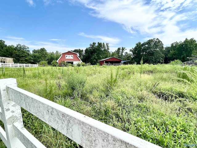 view of yard featuring a rural view, fence, and an outdoor structure