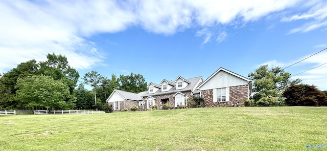 new england style home featuring a front lawn, fence, and brick siding