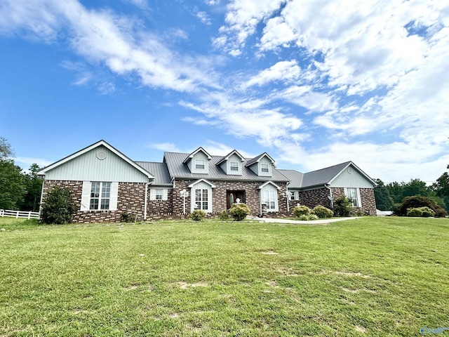 view of front facade featuring metal roof, brick siding, fence, and a front lawn