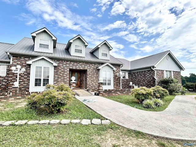 view of front of home with a standing seam roof, brick siding, and metal roof