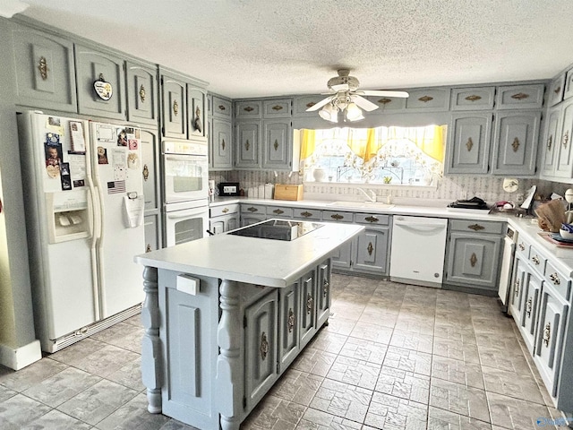 kitchen featuring gray cabinets, light countertops, decorative backsplash, a sink, and white appliances