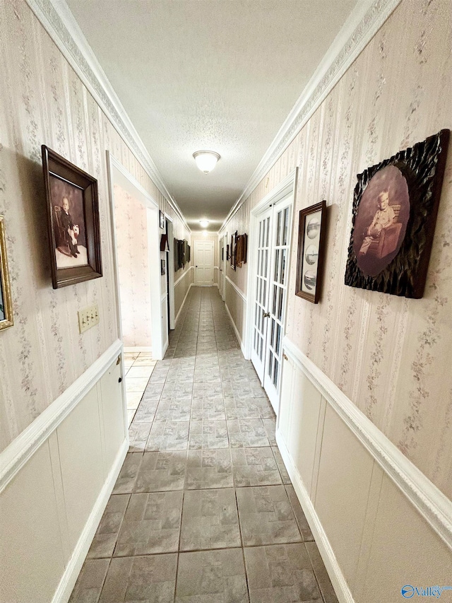 hall with ornamental molding, a textured ceiling, light tile patterned floors, and french doors