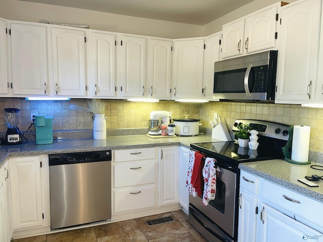 kitchen featuring tasteful backsplash, white cabinetry, stainless steel appliances, and a textured ceiling