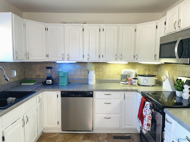 kitchen with white cabinets, decorative backsplash, sink, and appliances with stainless steel finishes