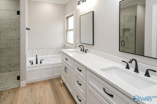 bathroom with plus walk in shower, dual vanity, crown molding, and hardwood / wood-style flooring