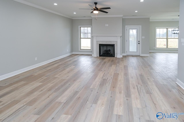 unfurnished living room with crown molding, light hardwood / wood-style floors, a tile fireplace, and ceiling fan