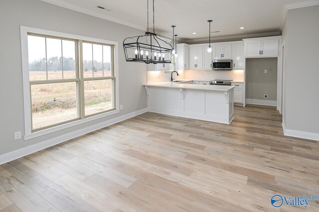 kitchen with stainless steel appliances, white cabinets, kitchen peninsula, light wood-type flooring, and a chandelier