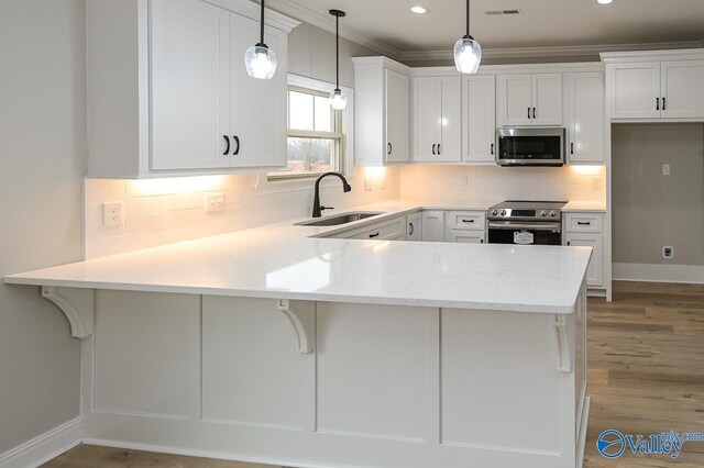 kitchen with sink, appliances with stainless steel finishes, kitchen peninsula, and light hardwood / wood-style floors