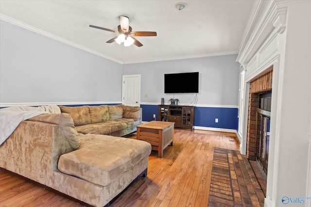 living room with ceiling fan, hardwood / wood-style flooring, a fireplace, and crown molding