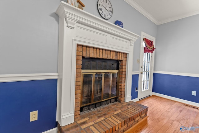 unfurnished living room with a brick fireplace, hardwood / wood-style flooring, and ornamental molding