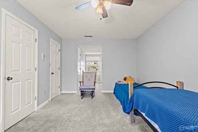 carpeted bedroom with ceiling fan and a textured ceiling