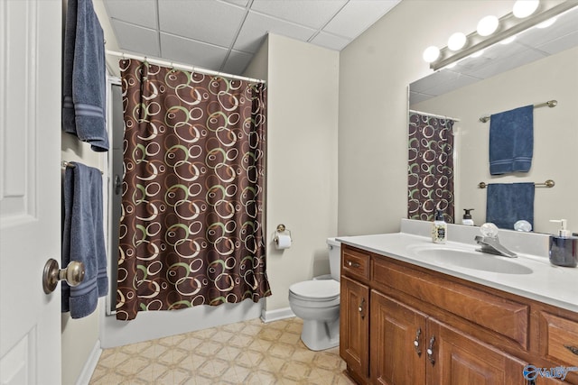 full bathroom featuring vanity, a drop ceiling, toilet, and shower / bathtub combination with curtain