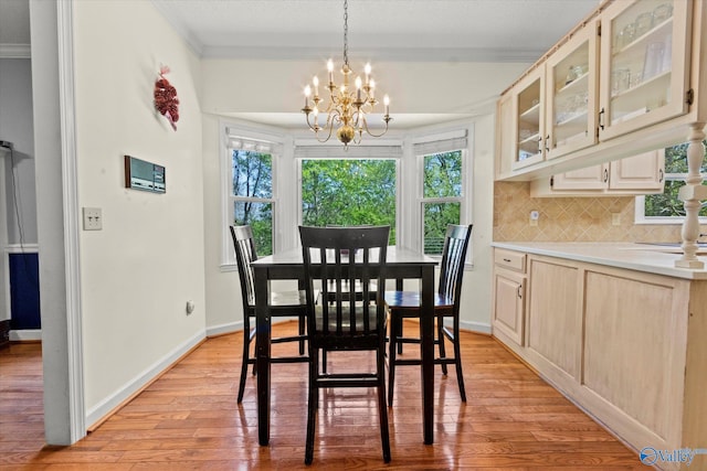 dining space with light hardwood / wood-style flooring, crown molding, and a chandelier