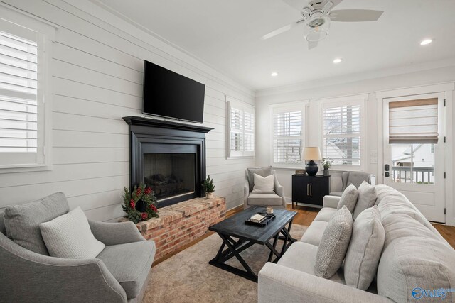 living area with ornamental molding, a fireplace, wood finished floors, and recessed lighting