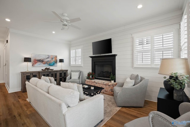 living area featuring recessed lighting, a brick fireplace, wood finished floors, and crown molding