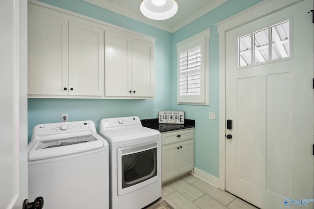 washroom featuring washing machine and dryer, cabinet space, and baseboards