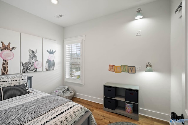 bedroom featuring a barn door, visible vents, baseboards, wood finished floors, and recessed lighting