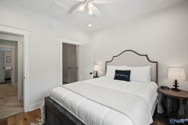 bedroom with parquet floors, attic access, baseboards, and a ceiling fan